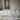 Made bed dressed in a white bedding set with folded grey and white duvets in a bright bedroom